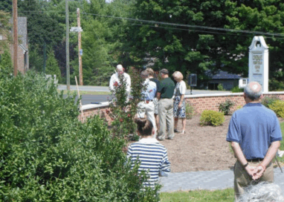 A small group of people gathers near a landscaped area. A sign for "Town of Taylor" is partially visible in the background.